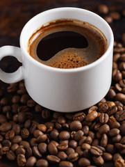 White Cup of espresso close-up on roasted coffee beans
