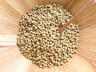 Top view of soy beans in a wooden bowl and wooden spoon for soybean seed scoop
