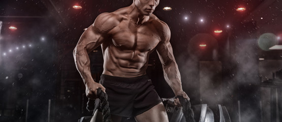 Male athlete bodybuilder posing on a black background