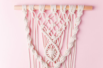 A handmade 100% cotton macrame wall decoration hanging on pink wall. Decoration for the interior. Trendy handcrafted decor for house