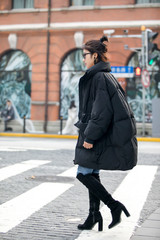 Obraz premium Stylish Asian girl wearing long black down jacket on the street