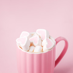 Pink light pastel background. Cup of dark coffee, hearts shaped marshmallow. Valentine's wedding day concept. Romantic girly femininy background