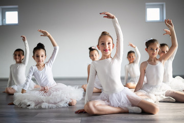 Group of fit happy children exercising ballet in studio together