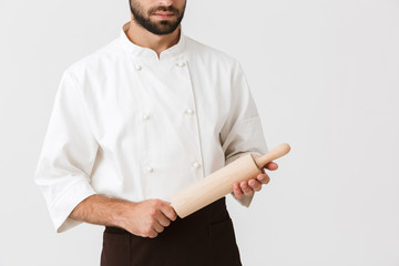 Cropped image of young chief man in cook uniform holding kitchen wooden rolling pin