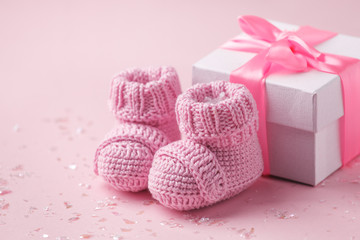 Pair of small baby socks and gift box on pink background with copy space for your warm message, baby shower, first newborn party background, copy space