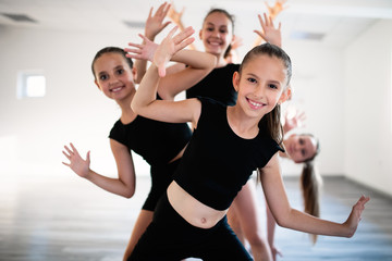 Group of fit happy children exercising ballet in studio together © NDABCREATIVITY