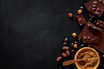 Chocolate bars and nuts on black table background top view mockup