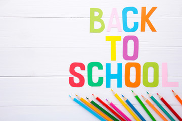 Inscription Back To School with school supplies on white wooden background