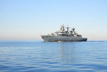 Grey modern warship sailing in still water