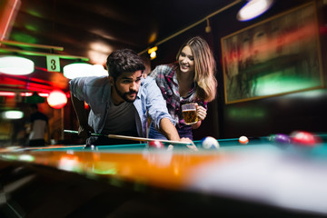 Couple dating, flirting and playing billiard in a pub