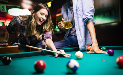 Young couple playing snooker together in bar