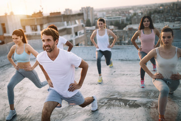 Group of fit healthy friends, people exercising together outdoor on rooftop