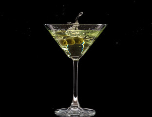 a glass of martini and a splash from falling olives