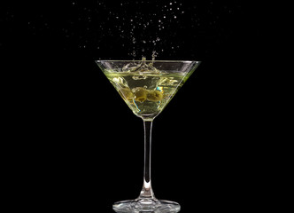 a glass of martini and a splash from falling olives