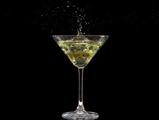 a glass of martini and a splash from falling olives