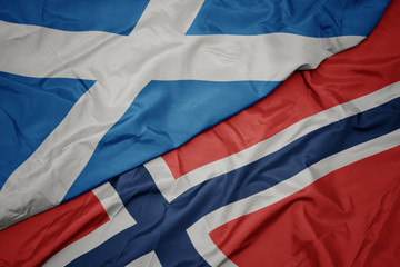 waving colorful flag of norway and national flag of scotland.