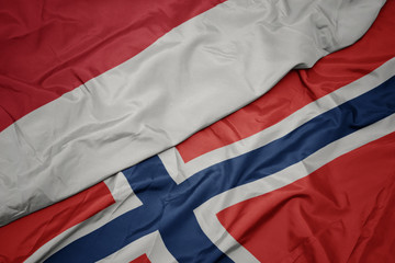 waving colorful flag of norway and national flag of indonesia.