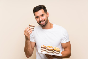 Handsome man holding muffin cake over isolated background