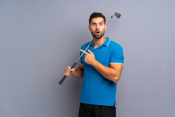 Handsome young man playing golf surprised and pointing side