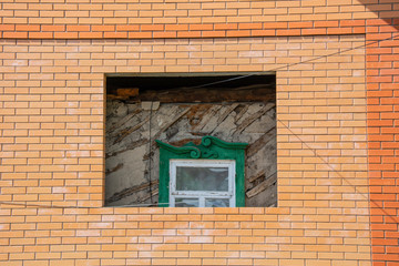 Old house with old green window inside brick and new house. Home under construction. Renovation