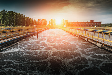 Wastewater treatment plant at sunset. Tanks for aeration and cleaning of sewage mass - obrazy, fototapety, plakaty