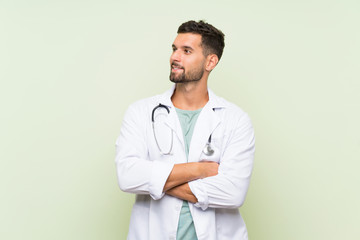 Young doctor man over isolated green wall laughing