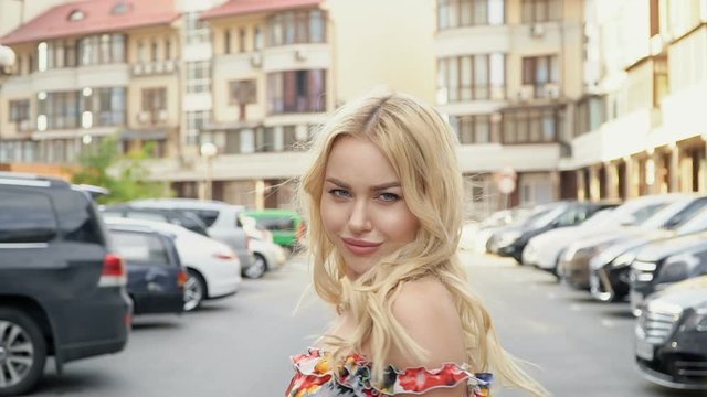 Blonde in a summer dress posing in the parking lot. Camera Wiring. Women's Gait