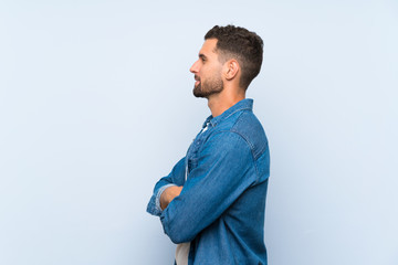 Handsome man over isolated blue background in lateral position