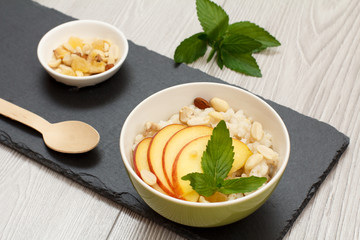 Sorghum salad with nuts and fresh peach on black stone board.
