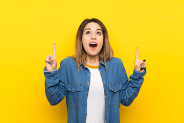 Young woman over yellow background pointing with the index finger a great idea