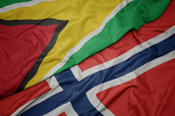 waving colorful flag of norway and national flag of guyana.