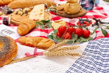 Stylish picnic on the green lawn. Fresh croissants and a teapot with tea on a bedspread near a wicker female hat. Instagram content