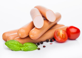 Classic boiled meat pork sausages with pepper and basil and cherry tomatoes on white background.