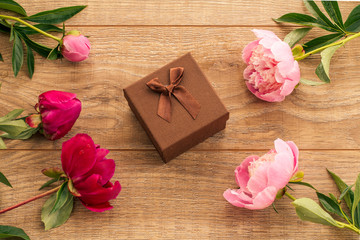 Gift box on wooden boards with peony flowers.