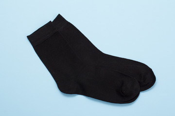 Pair of black woolen men socks on blue background.