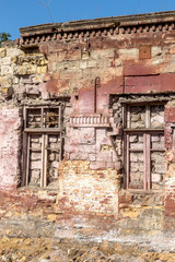 Fototapeta na wymiar Old wall of destroyed house. Old powder wall with walled window and gates, doors. Ruined house. Remains of old houses. Apocalypse Abandoned city Broken building. Effects of earthquake, economic crisis