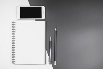 Top view of open notebook with stationery on black and white background