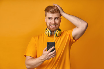 A puzzled young man with red beard forgets about something, touches head, clenches teeth, looks...
