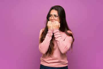 Teenager girl over purple wall nervous and scared putting hands to mouth - obrazy, fototapety, plakaty