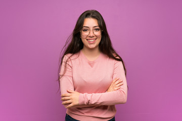 Fototapeta premium Teenager girl over purple wall with glasses and smiling