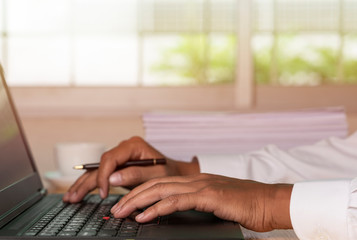 Asian businessman hands on the keyboard Working at home office with laptop,Data Processing business concept.