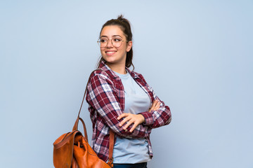 Teenager student girl over isolated blue wall with arms crossed and happy