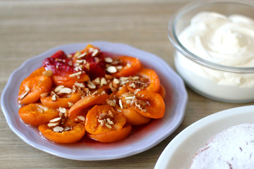 Plate of cooked apricots and peaches, served with syrup, walnuts and almonds. Selective focus.