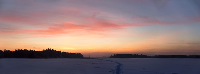 Fototapeta na wymiar Sonnenuntergang über dem Schneefeld mit schönen Abendrot Himmel