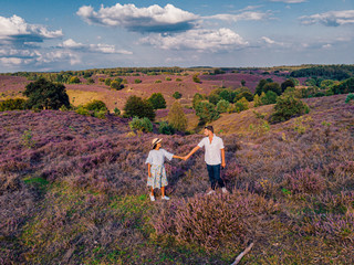 young couple men and woman hiking in the hills of the blooming heather field by the Posbank Veluwezoom Netherlands