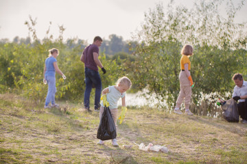 family picks up trash on the beach in summer