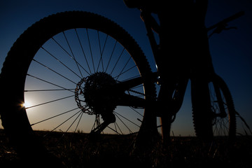 Silhouette of the bikecycle against the blue sky at sunset