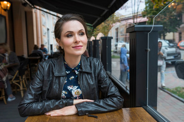 A beautiful young girl with a makeup and hairdo sitting in the cafe at the summer terrace.