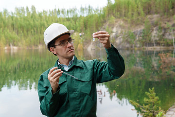 industrial ecologist visually evaluates the response of a water sample from lake at the site of a...