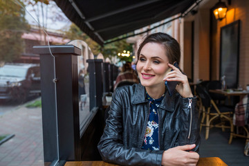 A portrait of a young woman speaking over a cell phone in the cafe.